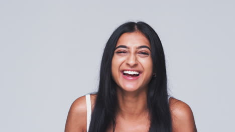 cabeza y hombros foto de estudio de una mujer tirando caras y sonriendo a la cámara en cámara lenta