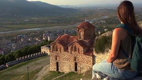 Woman-sits-in-front-of-a-monastery-in-Berat---Albania-with-a-beautiful-view-of-the-valley