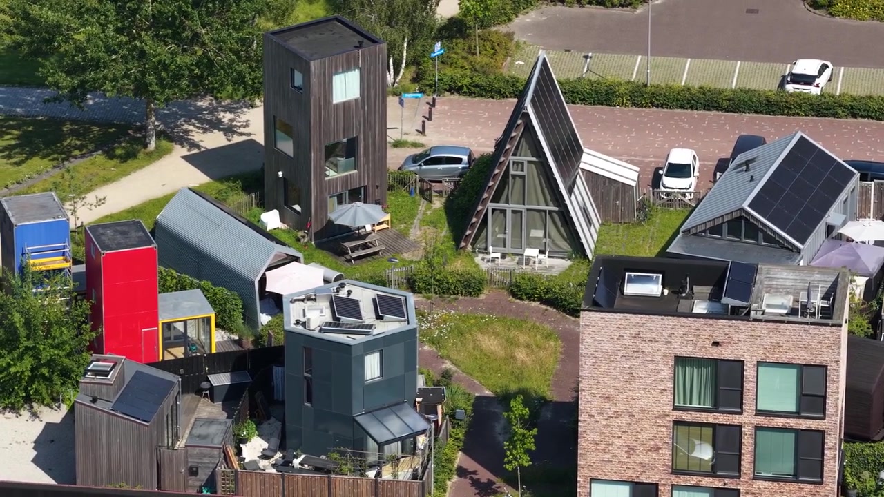Luftfoto af små huse i en økolandsby, der viser selvforsynende livsstil, solpaneler, grønt boligdesign og et bæredygtigt samfundsmiljø