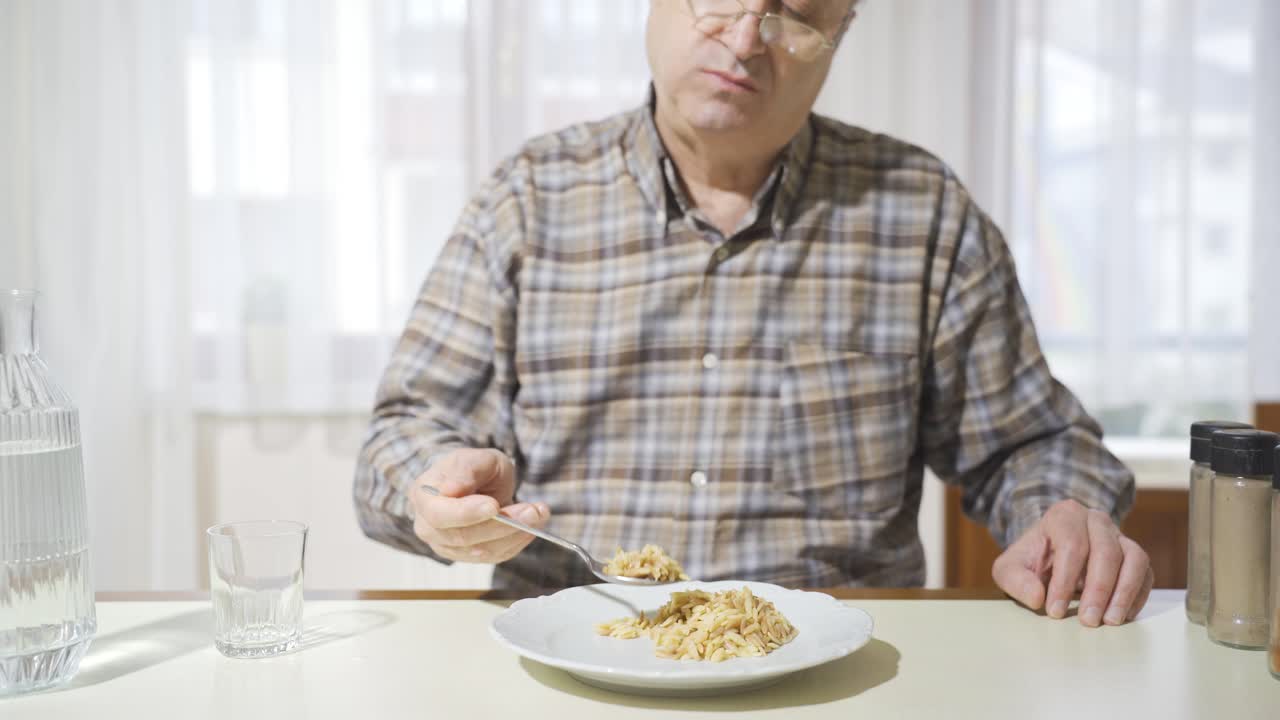 un viejo jubilado feliz comiendo en la cocina.