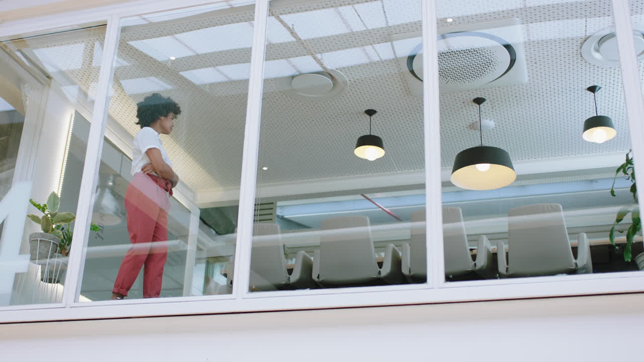 mujer de negocios de raza mixta mirando por la ventana de la oficina contemplando una carrera disfrutando del liderazgo corporativo joven empresaria planeando adelante para un futuro positivo imágenes de 4k