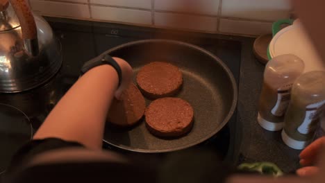 vista sobre el hombro de un cocinero cocinando hamburguesas vegetarianas en una estufa en cámara lenta de 4k