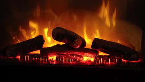 hand-held shot of a electronic fireplace warming up with wooden logs on fire