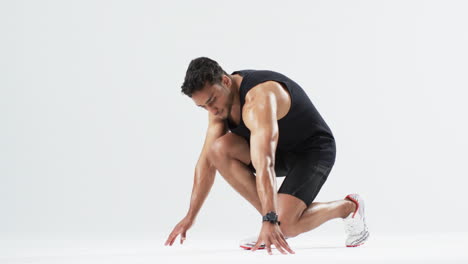 Athletic-young-biracial-man-prepares-to-sprint,-with-copy-space-on-white-background