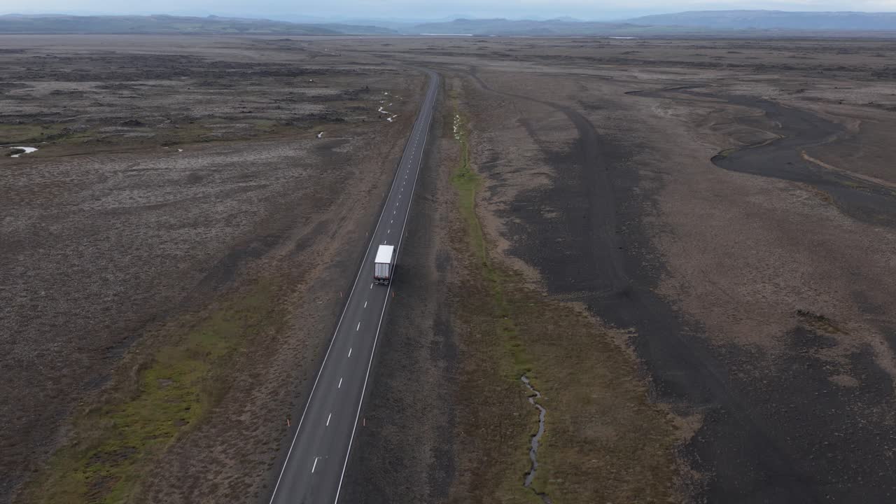 Truck driving endless road in flat volcanic Iceland landscape, Hringvegur ring road, aerial