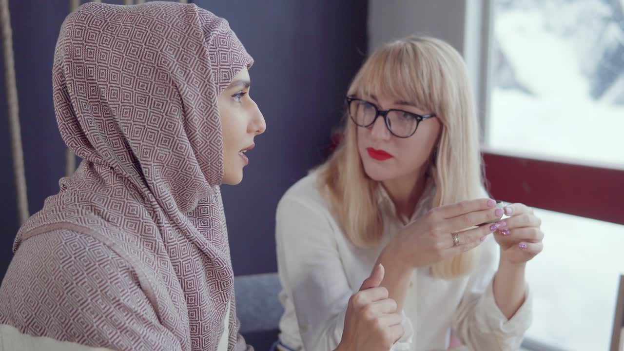 두 여인이 커피를 마시며 토론하고 있습니다.