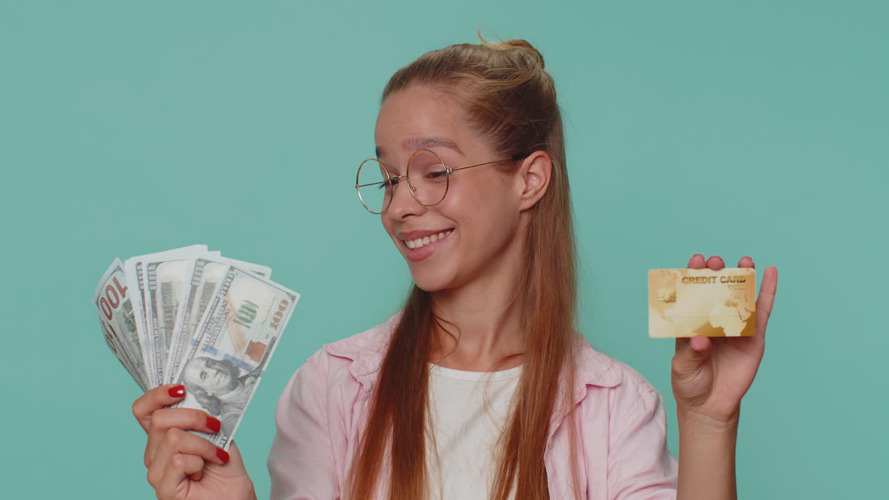 Ragazza felice mostra una carta di credito bancaria in plastica, pubblicizzando trasferimenti di denaro senza contanti e acquisti online.