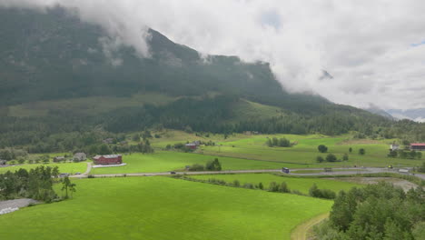 Vehicles-Traveling-On-Country-Road-Through-Green-Fields