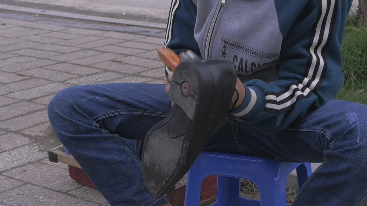 Poor boy shineing shoes on the street in Vietnam Slow Motion