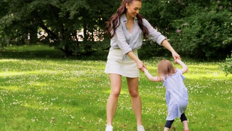 Happy-Mother-with-Little-Daughter-Playing-at-Park.family,-motherhood-and-people-concept-happy-mother-with-little-daughter-playing-at-summer-park-or-garden