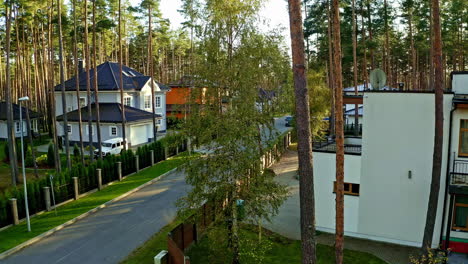 Aerial-drone-shot-along-rows-of-bunglows-surrounded-by-tall-trees-during-evening-time