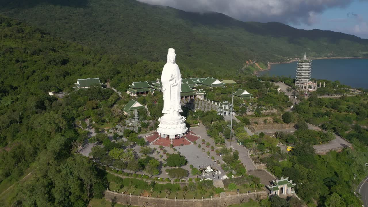 antena cercana de la estatua de buda de dama alta y templos con enormes montañas y océano en da nang, vietnam