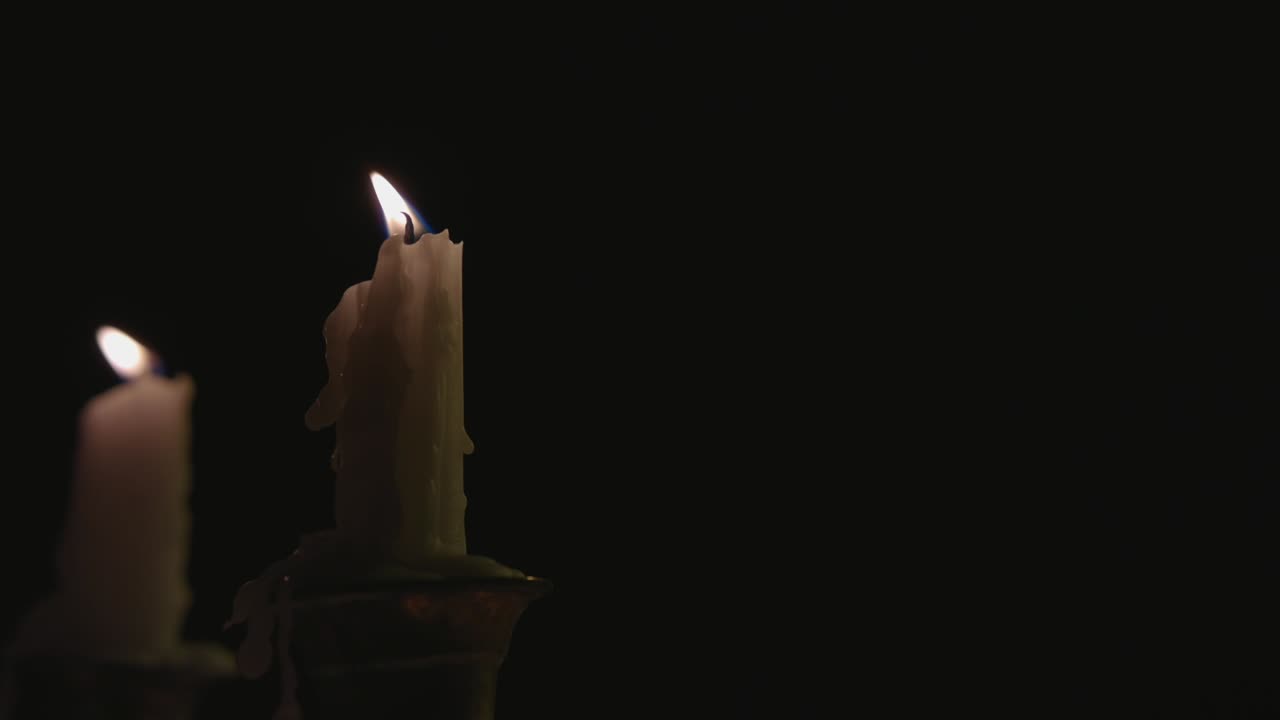 Un primo piano di due candele bianche accese su un candelabro al rallentatore