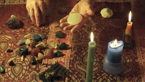 Close-up of hands performing alternative rituals with magic gems on a mystical table with curative stones and candles