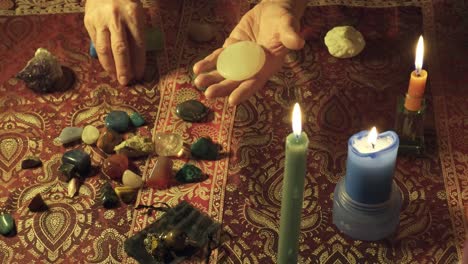 close-up of hands performing alternative rituals with magic gems on a mystical table with curative stones and candles