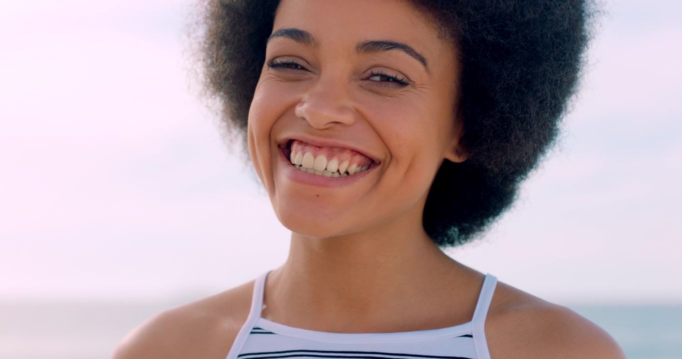 Giovane donna felice con capelli afro che sorride all'aperto