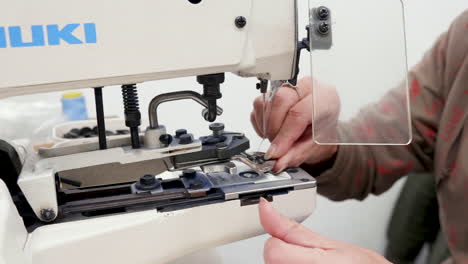 woman working on a sewing machine for buttons