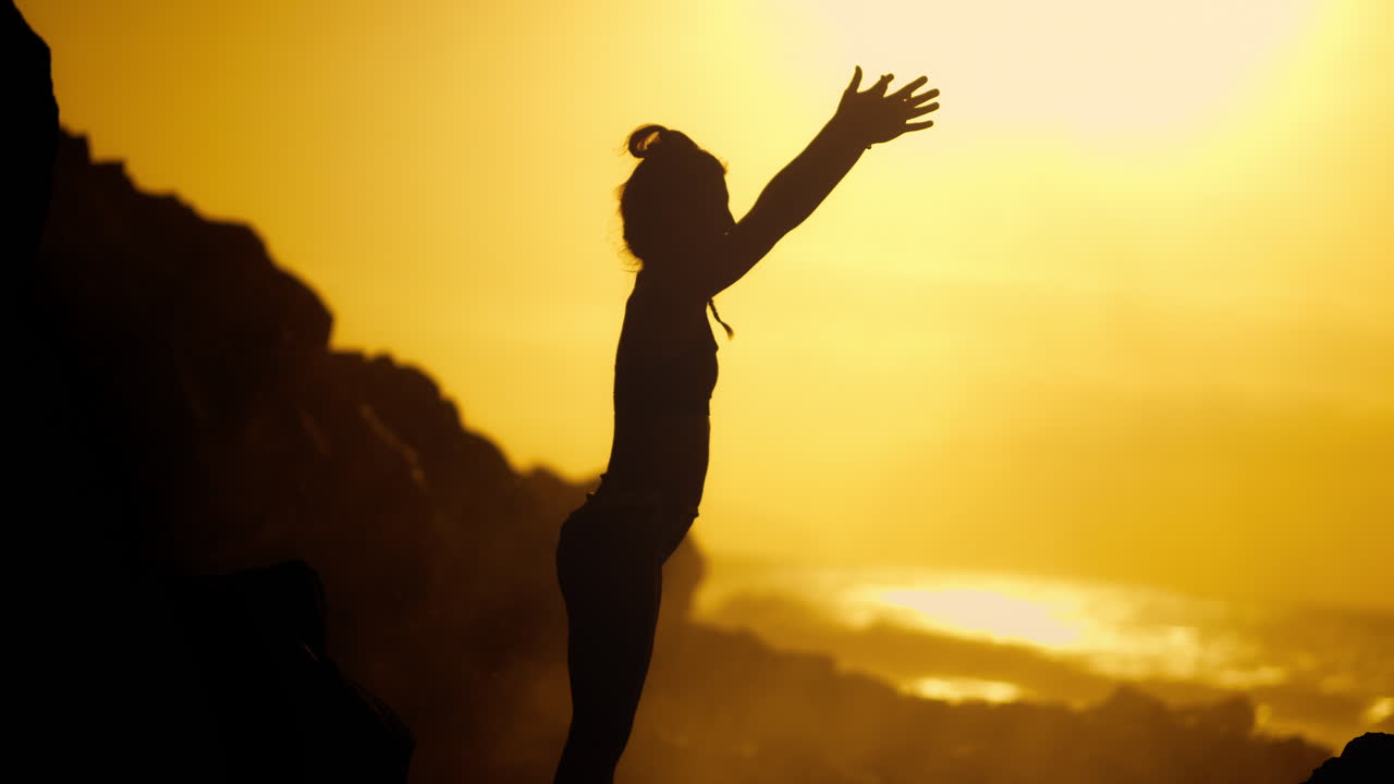Woman practicing yoga at sunset on the beach