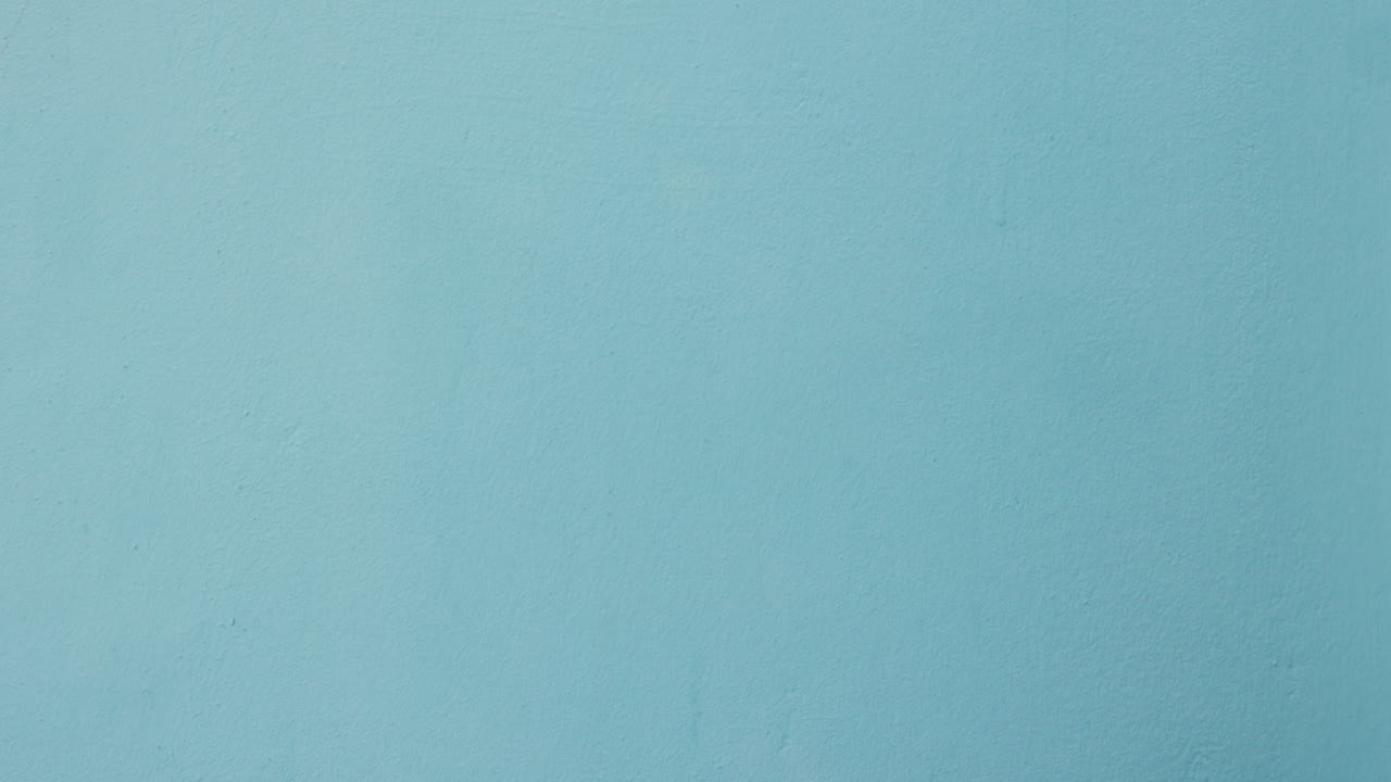 manos de mujer con signo de corazón contra la pared azul