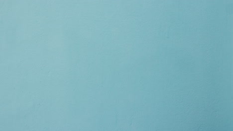 Woman-hands-with-heart-sign-against-wall-blue