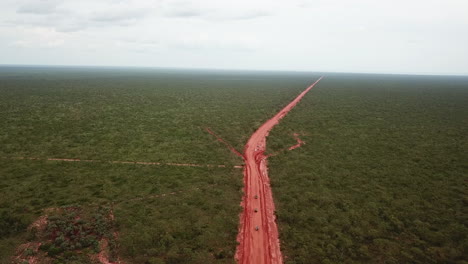 Aerial:-Drone-shot-following-three-off-road-vehicles-driving-up-an-orange-dirt-road-near-Broome,-Western-Australia