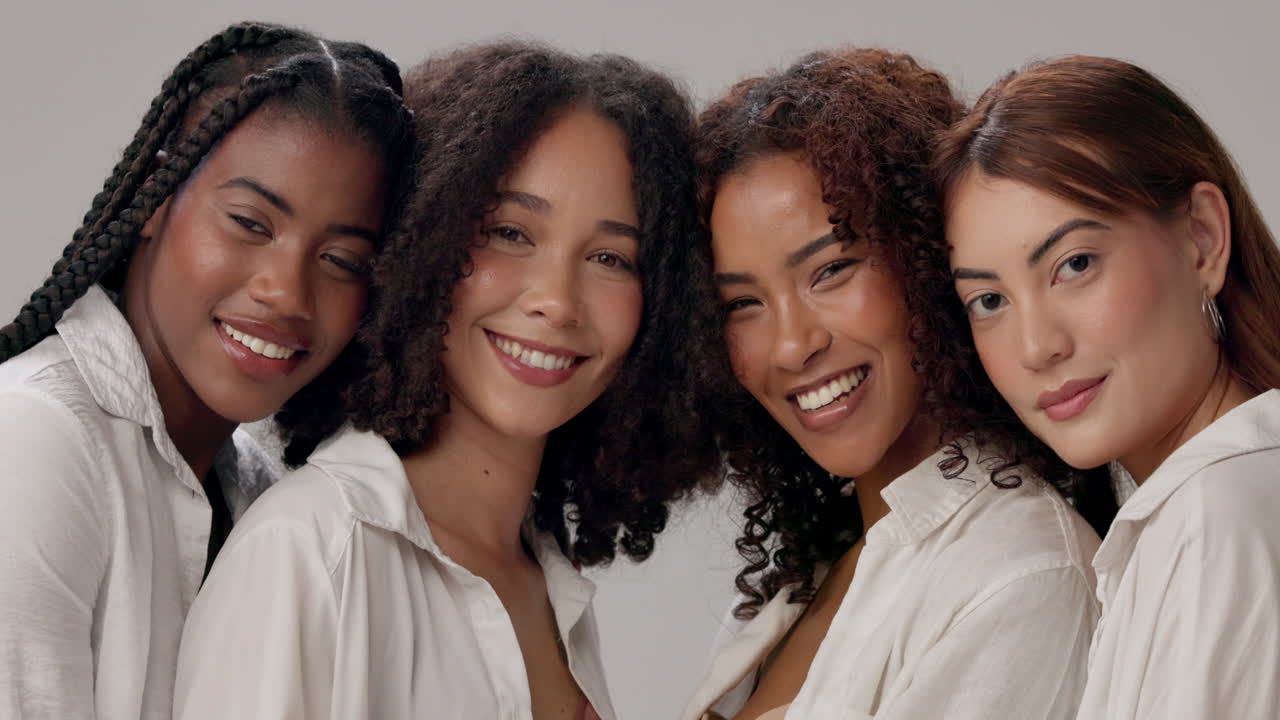 Four diverse women friends smiling and posing together in a studio portrait