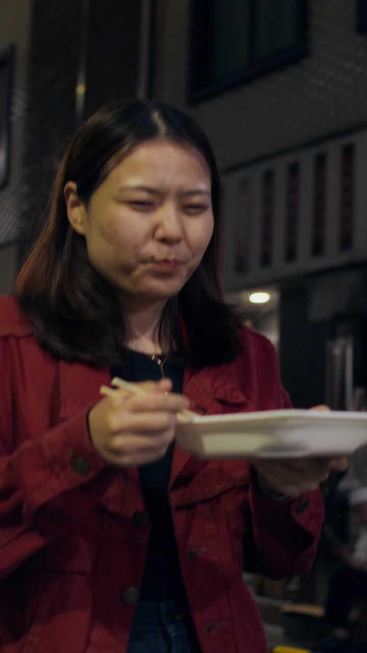 Woman eating street food at night
