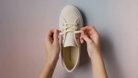 close-up of hands tying shoelaces on a white sneaker
