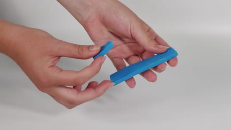 hands shaping blue plasticine into different forms