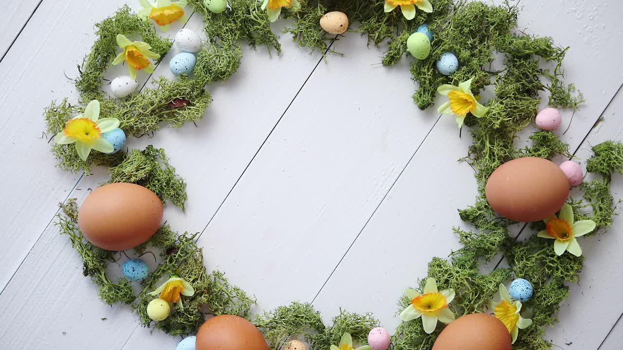 красочный декоративный венок из пасхальных яиц на фоне белого деревянного стола