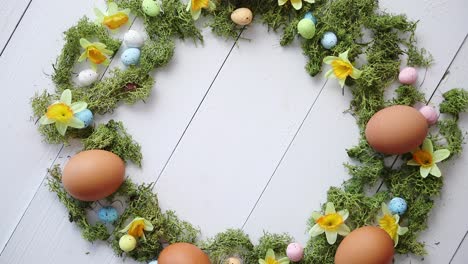 Colorful-decorative-Easter-eggs-wreath-on-white-wooden-table-background