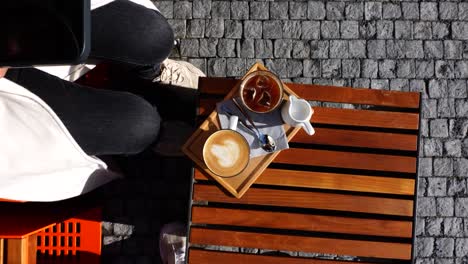 ice coffee and latte cup on wooden outdoor table while girl take a photo