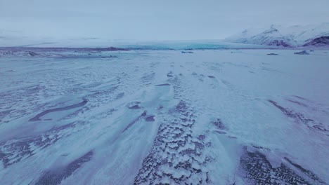 Vista-Panorámica-Aérea-Del-Paisaje-Sobre-La-Zona-Del-Lago-Congelado-Jokulsarlón,-Con-Icebergs-Cubiertos-De-Nieve,-En-Islandia,-Al-Atardecer