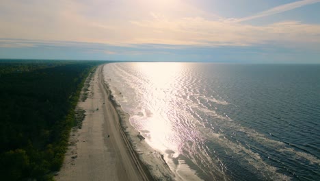 Reflection-of-sun-shining-in-sea-water-next-to-sandy-Baltic-beach-coastline-fixed-drone-image