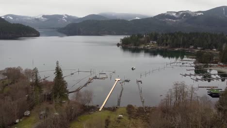 drone shot of lake, snowy mountains with docks in canada vancouver island