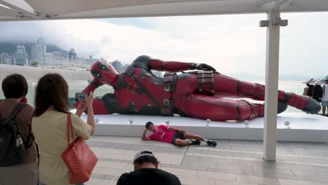 against hong kong’s skyline, an 8-meter deadpool installation draws locals and tourists, who snap photos to mark disney’s "deadpool and wolverine" film promotion.
