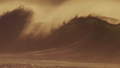 sideview as wave crashes into spray, soft early morning light dances across waves as offshore winds pull ocean spray mist over top