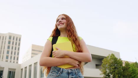 young woman with books and backpack on campus