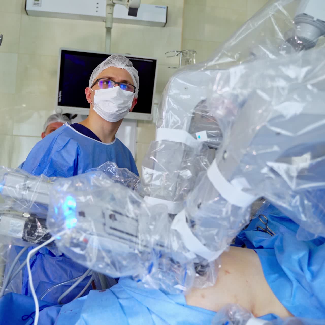Surgeon near robotic arms of medical equipment. Minimally invasive surgical procedure with medical robot in modern operating room. Futuristic operation