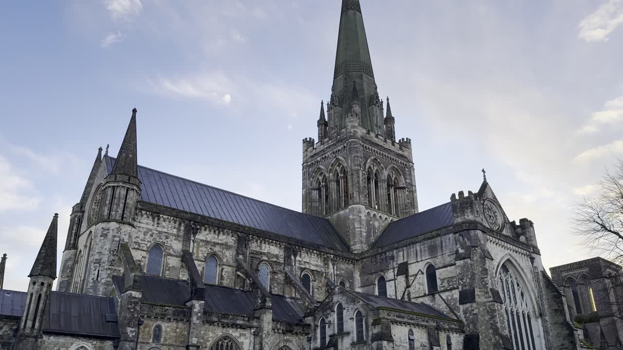 Centraltårn med spir over korsskæringen af Chichester Katedral mod en aftensky.