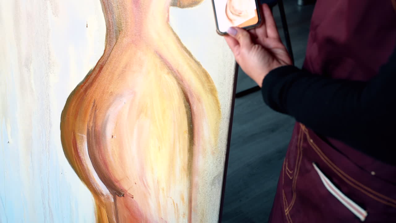 Man painting on a canvas with a woman holding up a reference at an art gallery workshop