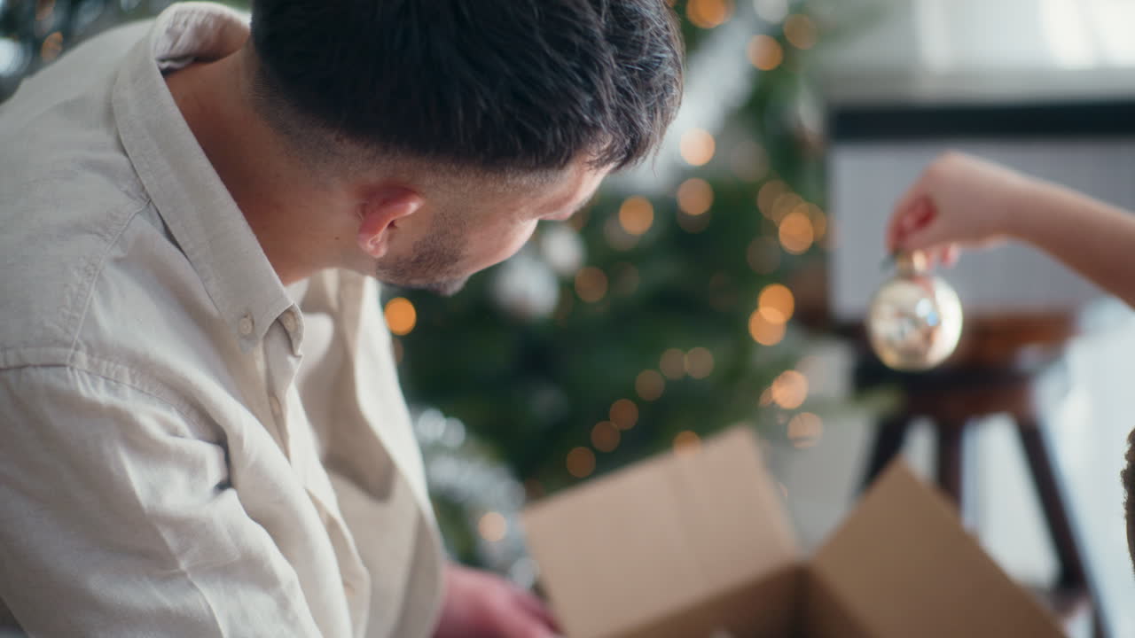 어린 소년은 상자 밖으로 유리 크리스마스 보블을 꺼낸다