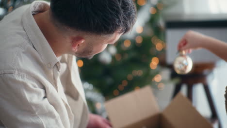 un niño toma una bola de cristal de navidad de la caja.