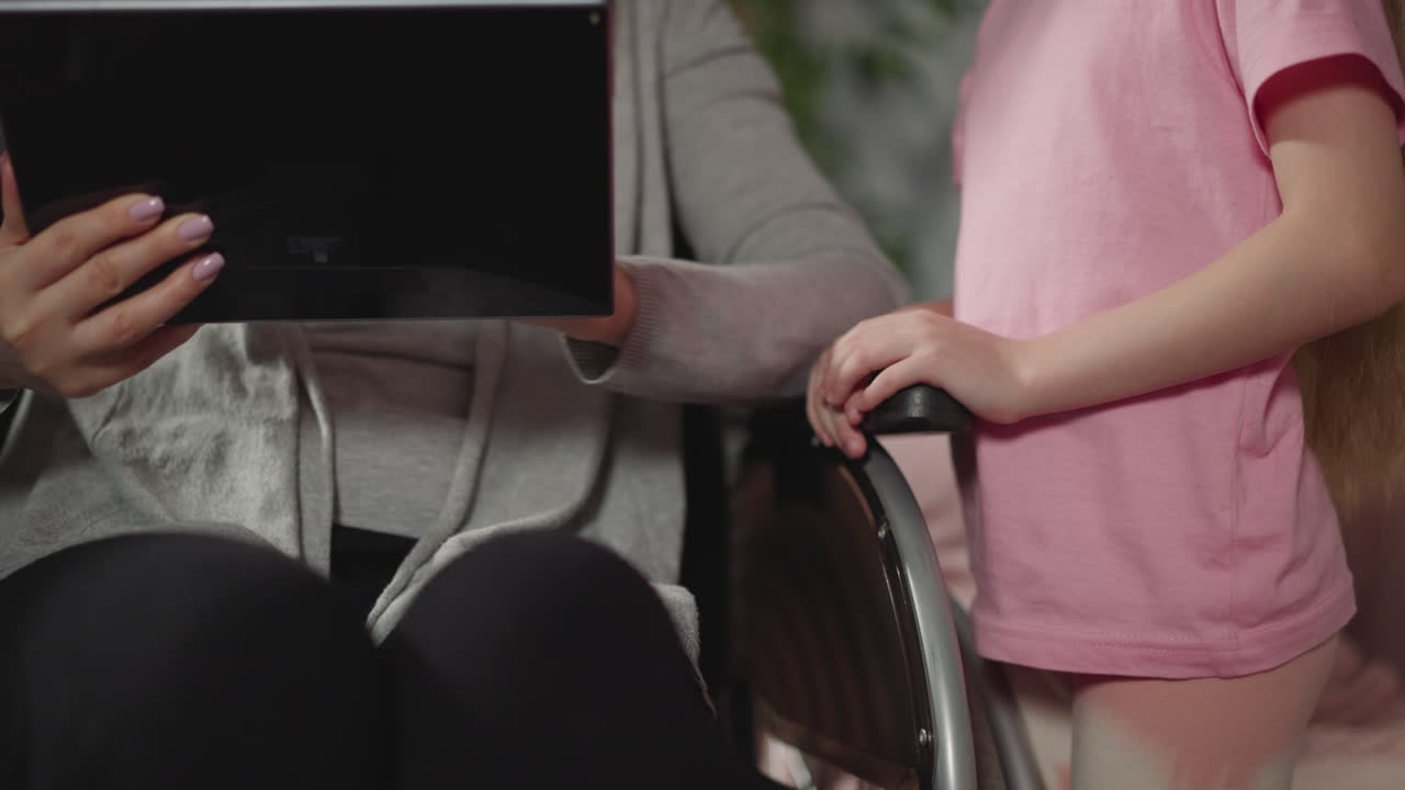 niña pequeña ve a su madre desplazándose por la red en la tableta