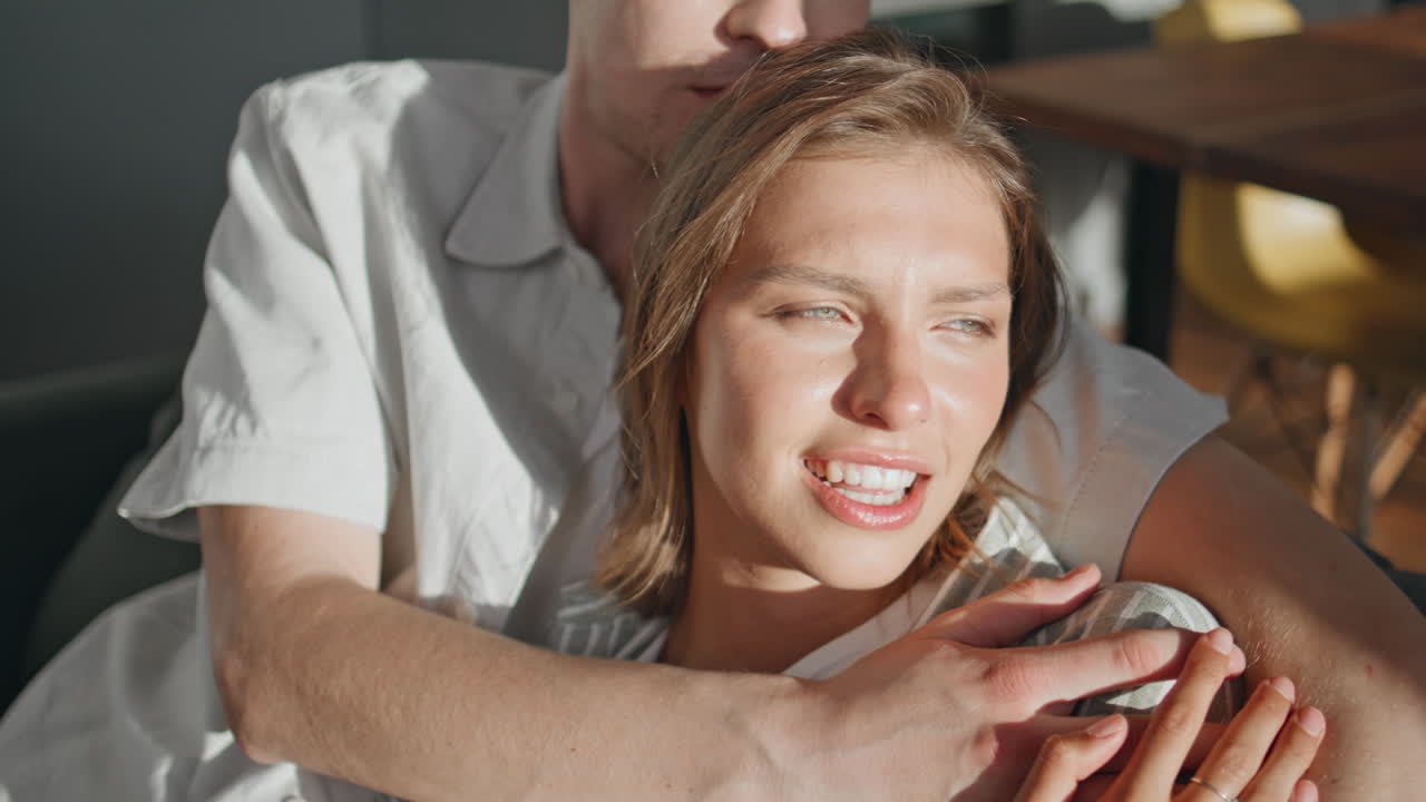 Primo piano di una ragazza che parla con l'amato marito alla luce del sole. Coppia romantica che si coccola sul divano