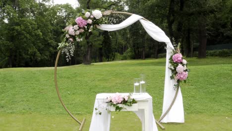 wedding altar, circular arch and chairs in park, backwards dolly shot