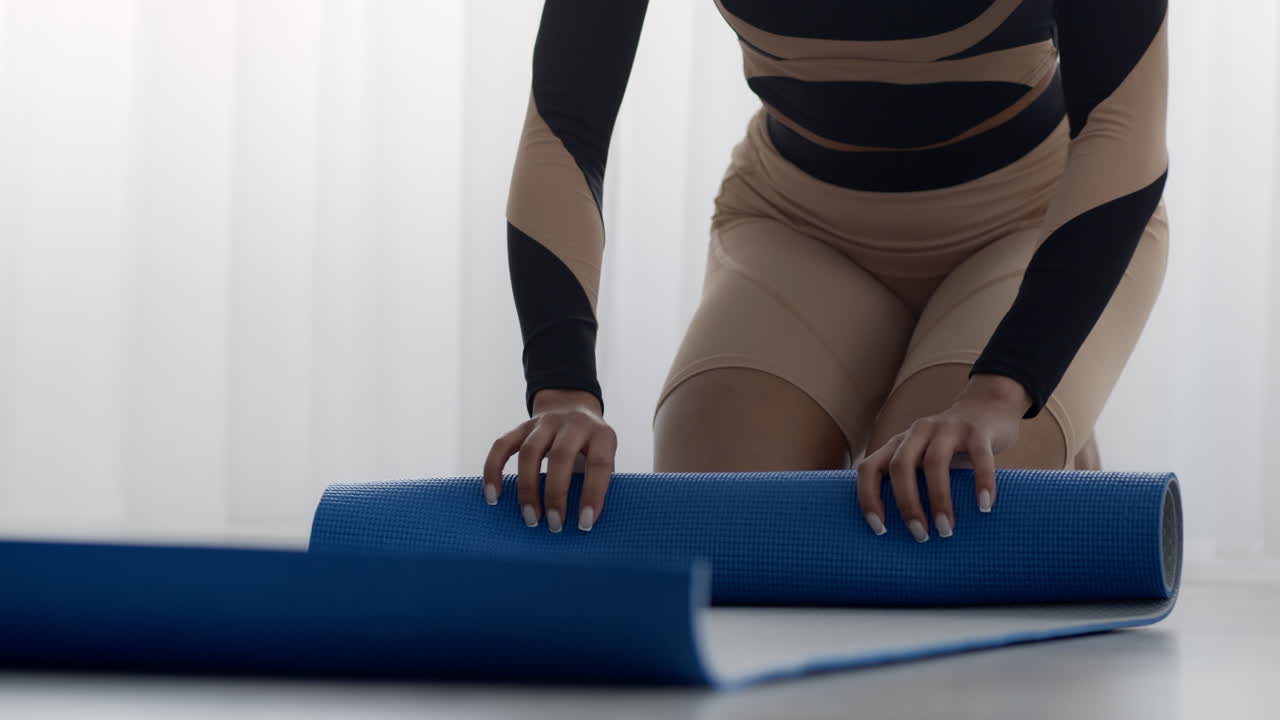 una mujer desplegando una alfombra de yoga.