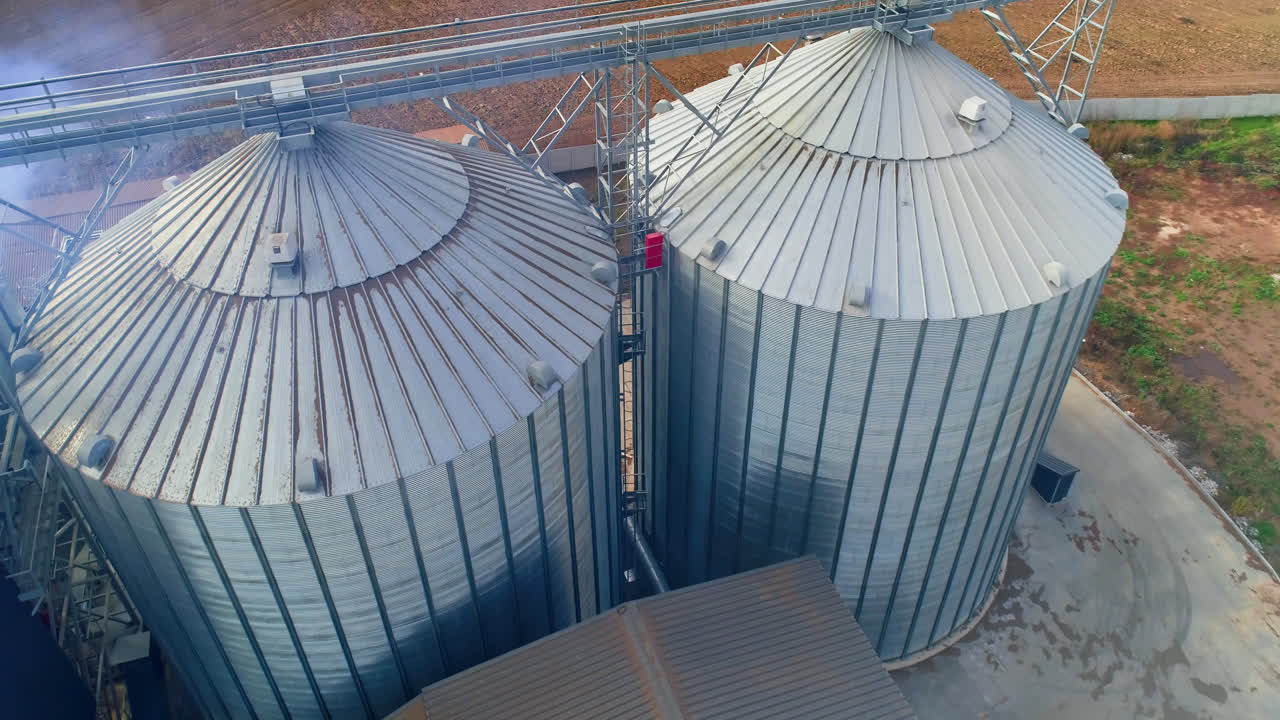 Special grain elevators for crop storage. Metal bridge from the roof of metal tank. View from above. Video from the top. Closeup.