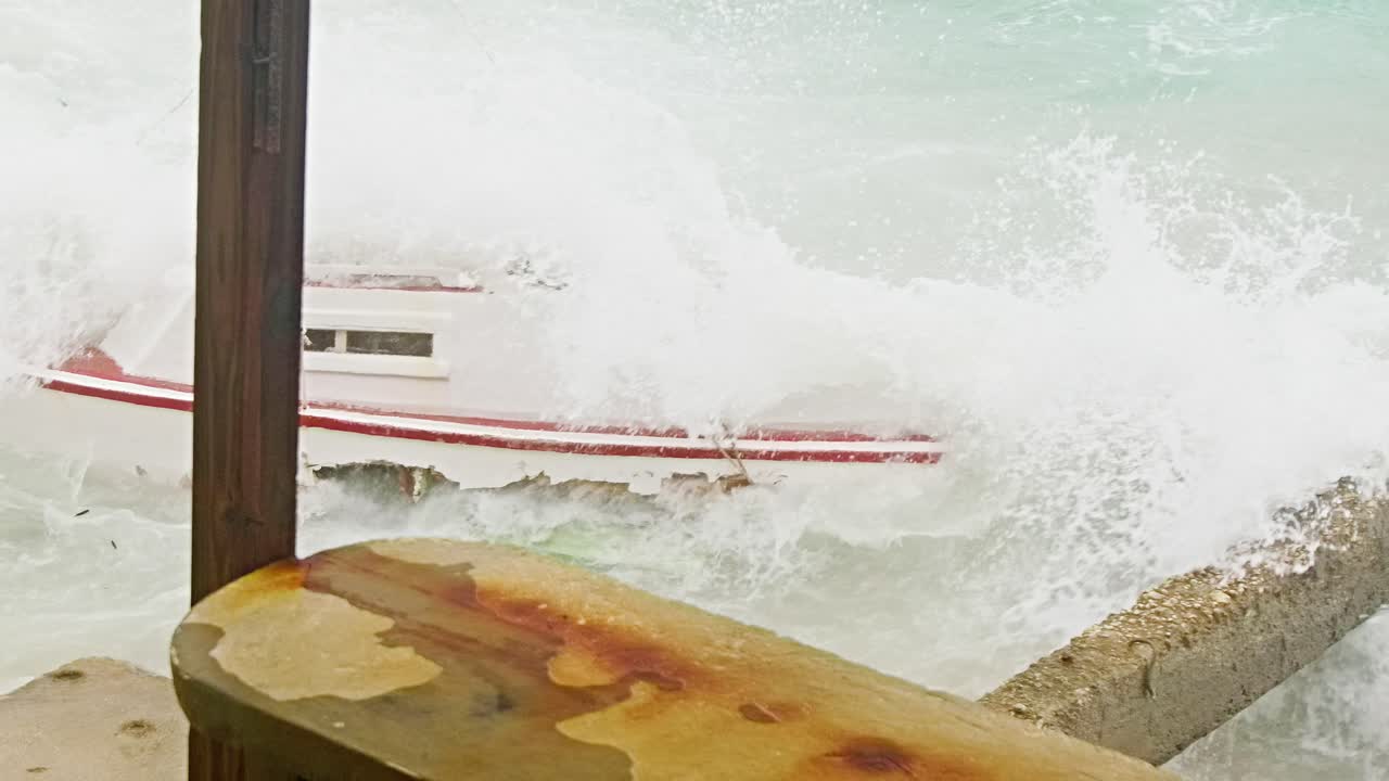 Close up slowmotion shot of local wooden fishing boat being smashed into pieces during sudden storm with rough waves, Caribbean