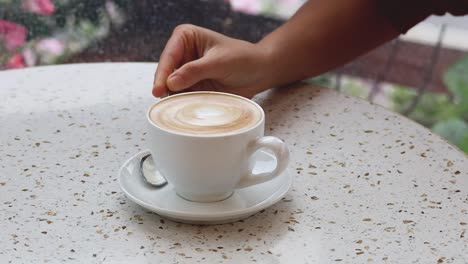 hand stirring coffee in a cup